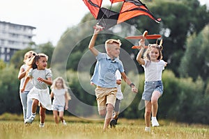 Happy children. Group of kids are running and playing with kite on green field