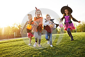 Happy children in Halloween costumes running on lawn