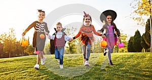 Happy children in Halloween costumes running on lawn