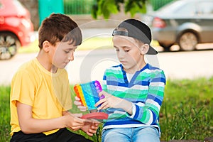 Happy children having fun outdoors. Cute boys playing with trendy pop it toy. Childhood, games and leisure for kids