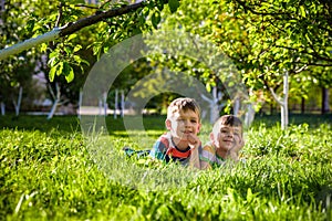 Happy children having fun outdoors. Kids playing in summer park. Little boy and his brother laying on green fresh grass holiday