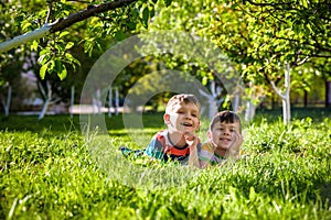 Happy children having fun outdoors. Kids playing in summer park. Little boy and his brother laying on green fresh grass holiday