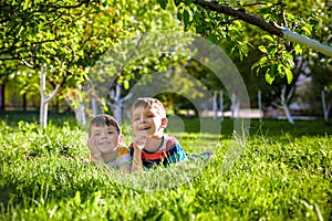 Happy children having fun outdoors. Kids playing in summer park. Little boy and his brother laying on green fresh grass holiday