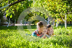 Happy children having fun outdoors. Kids playing in summer park. Little boy and his brother laying on green fresh grass holiday ca