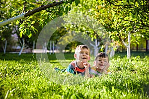 Happy children having fun outdoors. Kids playing in summer park. Little boy and his brother laying on green fresh grass holiday