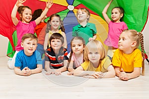 Happy children hiding under tent made of parachute