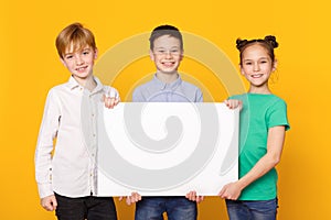 Happy children holding blank banner for advertisement