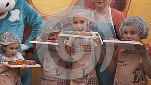 Happy children holding trays with delicious sweet doughnuts