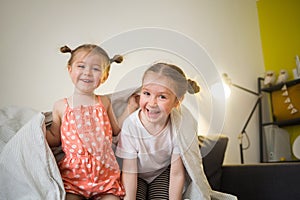 Happy children at home play on sofa bed.