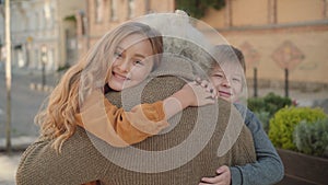 Happy children hugging male Caucasian retiree and smiling at camera. Portrait of joyful grandchildren meeting