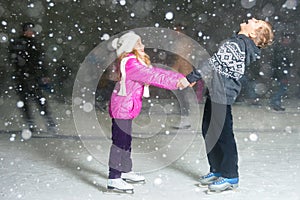 Happy children ice skating at ice rink, winter night