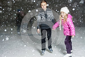 Happy children ice skating at ice rink, winter night