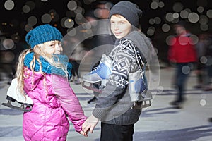 Happy children ice skating at ice rink, winter night