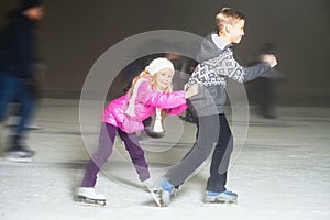 Happy children ice skating at ice rink, winter night