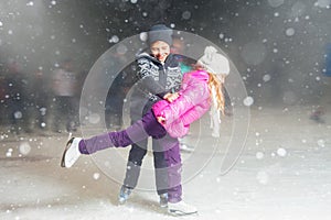 Happy children ice skating at ice rink, winter night