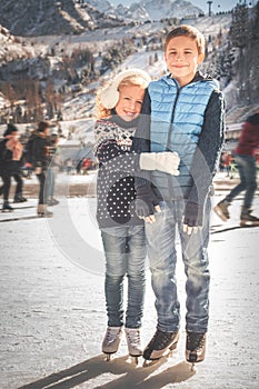 Happy children ice skating at rink outdoor