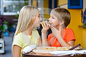 Happy children indoors eating pizza smiling