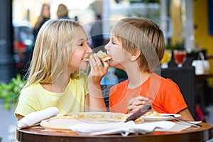 Happy children indoors eating pizza smiling