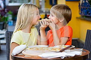 Happy children indoors eating pizza smiling