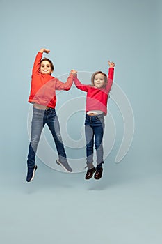 Happy children isolated on blue studio background. Look happy, cheerful, sincere. Copyspace. Childhood, education