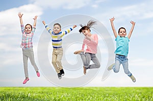 Happy children jumping in air over sky and grass
