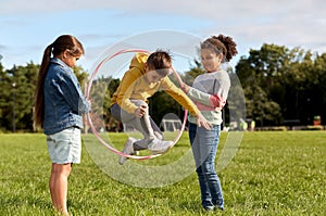 happy children jumping through hula hoop at park