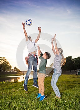 Happy children jumping and playing with ball