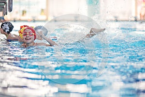 Happy children kids group at swimming pool class learning to swim