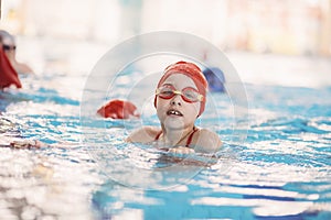 Happy children kids group at swimming pool class learning to swim