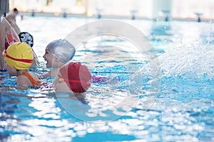 Happy children kids group at swimming pool class learning to swim