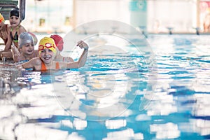 Happy children kids group at swimming pool class learning to swim