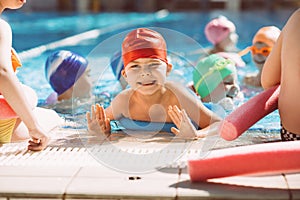 Happy children kids group at swimming pool class learning to swim