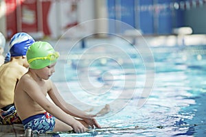 Happy children kids group at swimming pool class learning to swim