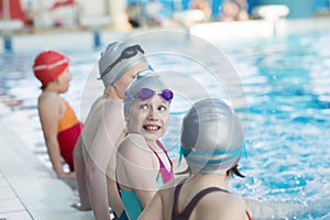 Happy children kids group at swimming pool class learning to swim