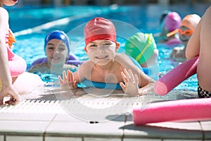 Happy children kids group at swimming pool class learning to swim