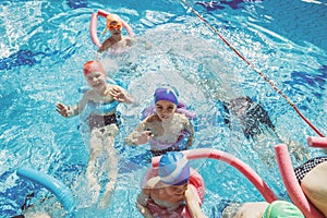 Happy children kids group at swimming pool class learning to swim