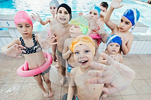 Happy children kids group at swimming pool class learning to swim