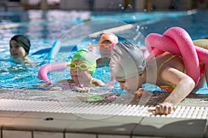 Happy children kids group at swimming pool class learning to swim