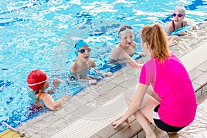 Happy children kids group at swimming pool class learning to swim