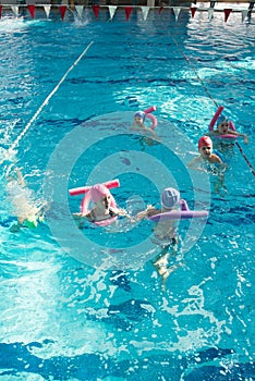 Happy children kids group at swimming pool class learning to swim