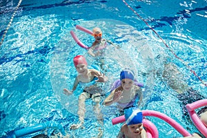 Happy children kids group at swimming pool class learning to swim