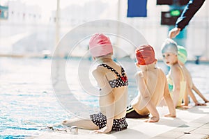 Happy children kids group at swimming pool class learning to swim