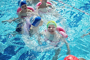 Happy children kids group at swimming pool class learning to swim