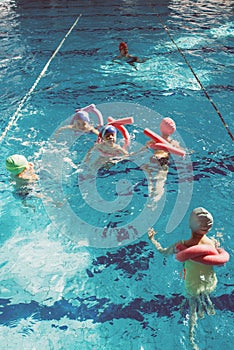 Happy children kids group at swimming pool class learning to swim