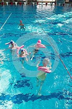 Happy children kids group at swimming pool class learning to swim