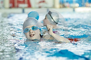 Happy children kids group at swimming pool class learning to swim