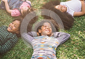 Happy children kids laying on grass in park.