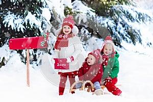 Children with letter to Santa at Christmas mail box in snow