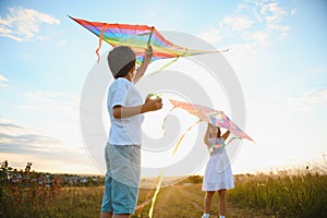 Happy children launch a kite in the field at sunset. Little boy and girl on summer vacation.