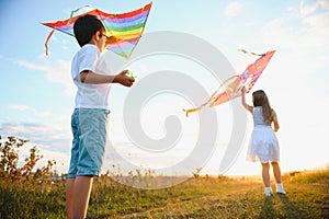 Happy children launch a kite in the field at sunset. Little boy and girl on summer vacation.